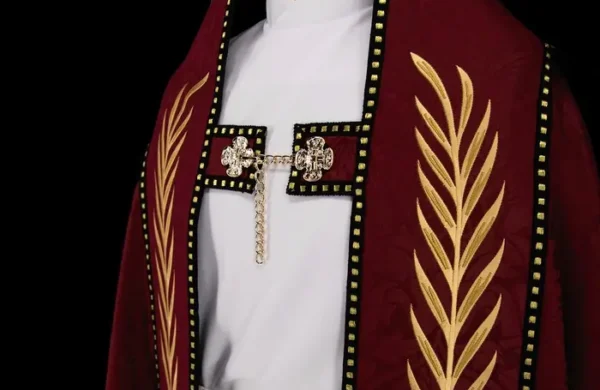 A close-up view of a liturgical garment with a red cope featuring intricate gold embroidery of palm leaves and ornate clasps.
