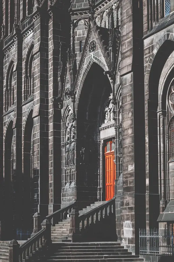 Exterior of Clermont-Ferrand Cathedral, France’s Black Church, showing its volcanic stone façade and striking red door